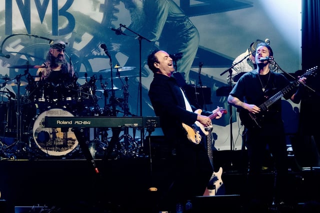 Neal Morse singing with his guitar between the drummer and a guitarist, the kick drum reading Netherlands